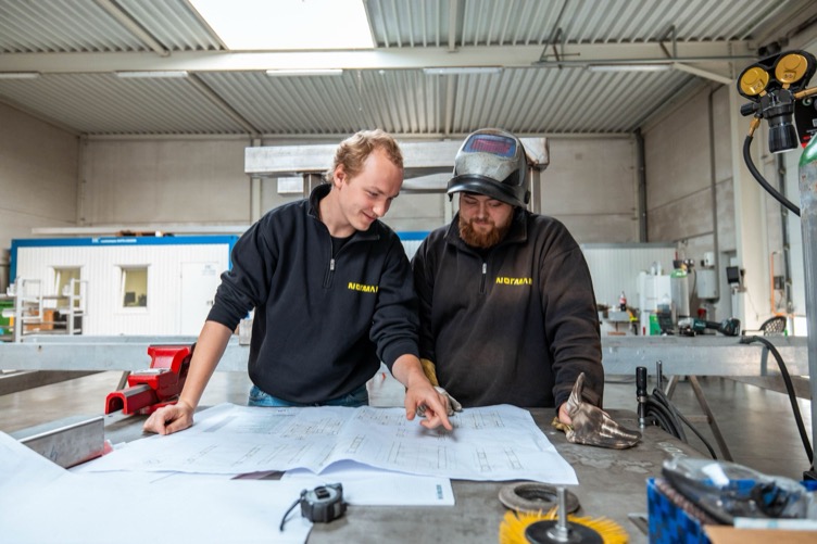 Engineering bij Nørman Twee Nørmannen bekijken samen een technische tekening in het atelier.